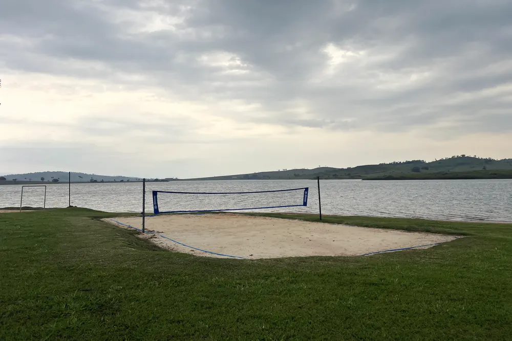 Quadra de areia com a represa ao fundo